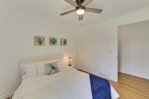 A bedroom with a bed, a ceiling fan, and three wall-mounted artworks. - Bike to Lake Michigan! Updated Home in Charlevoix (Charlevoix)