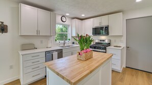Una cocina moderna con armarios blancos, una isla de madera, un microondas y un fregadero.