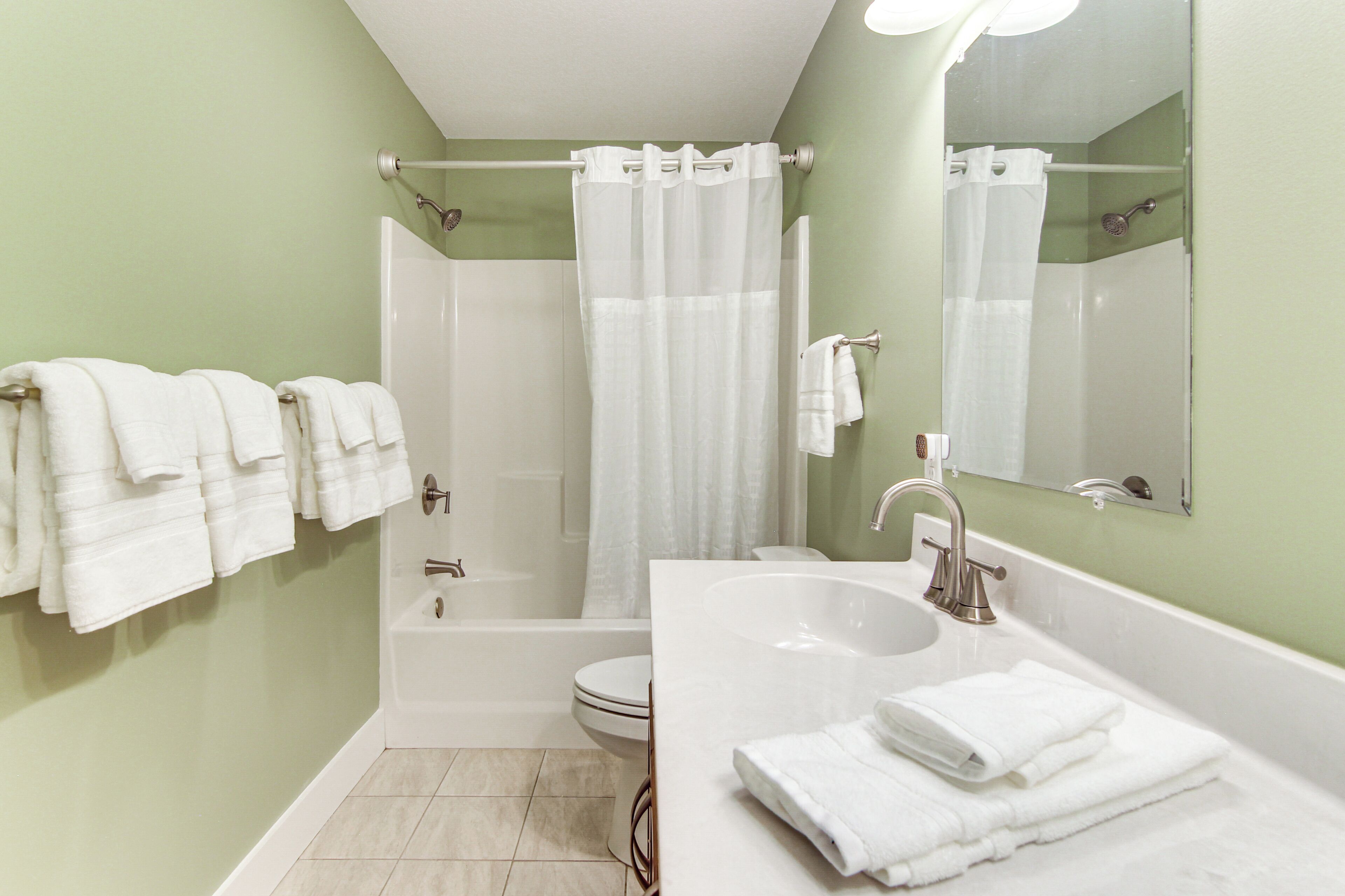A bathroom with a bathtub, a sink, and a toilet. There are towels hanging on the wall.