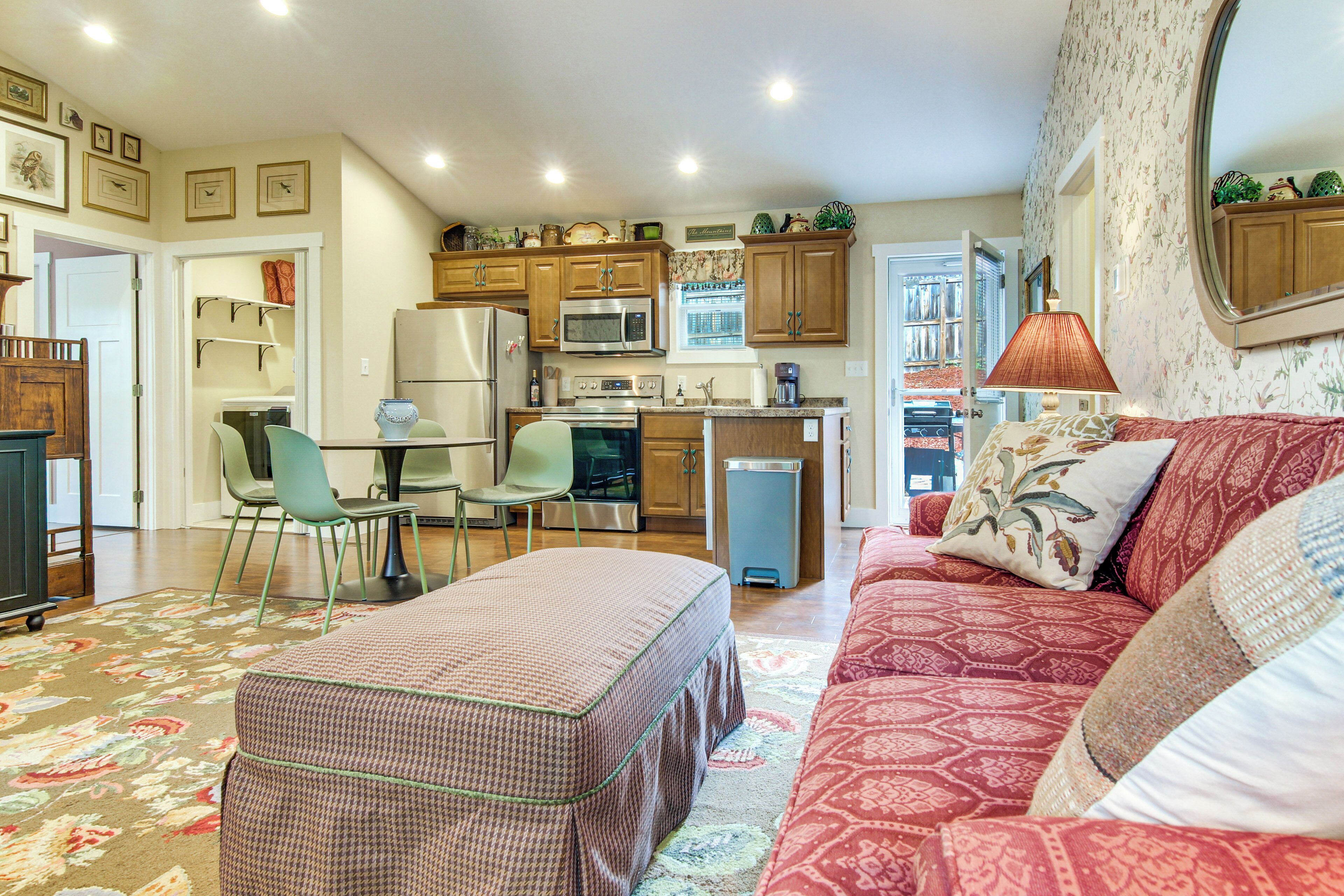 A compact living space with a kitchenette, a dining area, and a seating area with a sofa and ottoman.