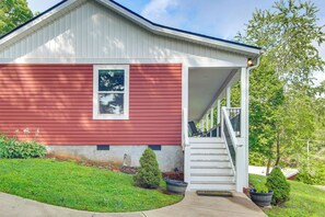 A single-story house with a red exterior, a front porch, and a staircase leading to the entrance. - Walk to Waynesville Hot Spots! 'woodland Cottage' (Waynesville)