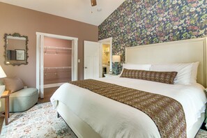 A bedroom with a bed, a nightstand, a lamp, a mirror, and a door. - Walk to Waynesville Hot Spots! 'woodland Cottage' (Waynesville)