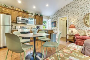 A modern kitchen with stainless steel appliances, a dining area with a round table and chairs, and a living room with a sofa and a patterned rug. - Walk to Waynesville Hot Spots! 'woodland Cottage' (Waynesville)