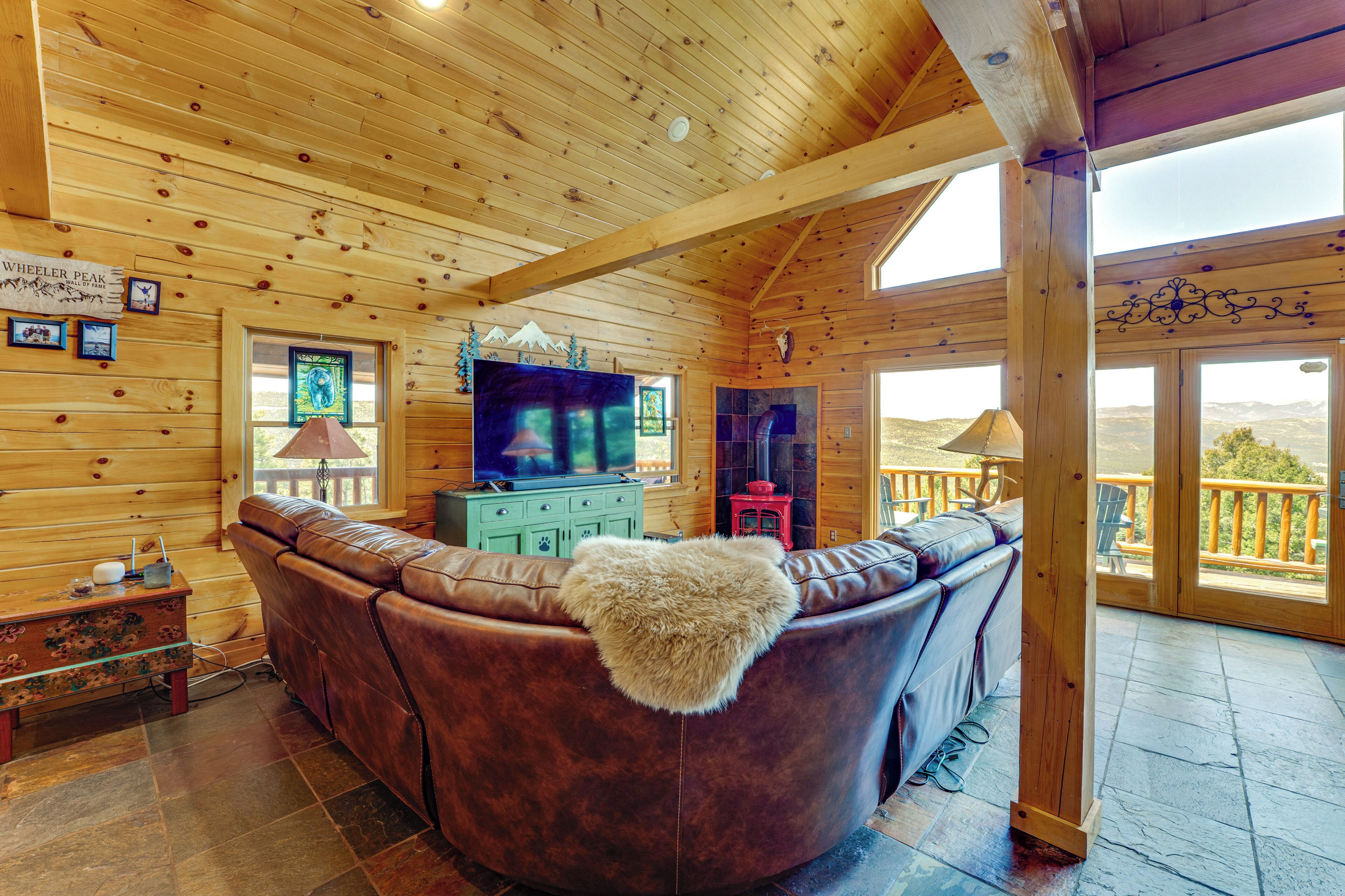 A wooden interior with a leather sofa, a television, and a fireplace.
