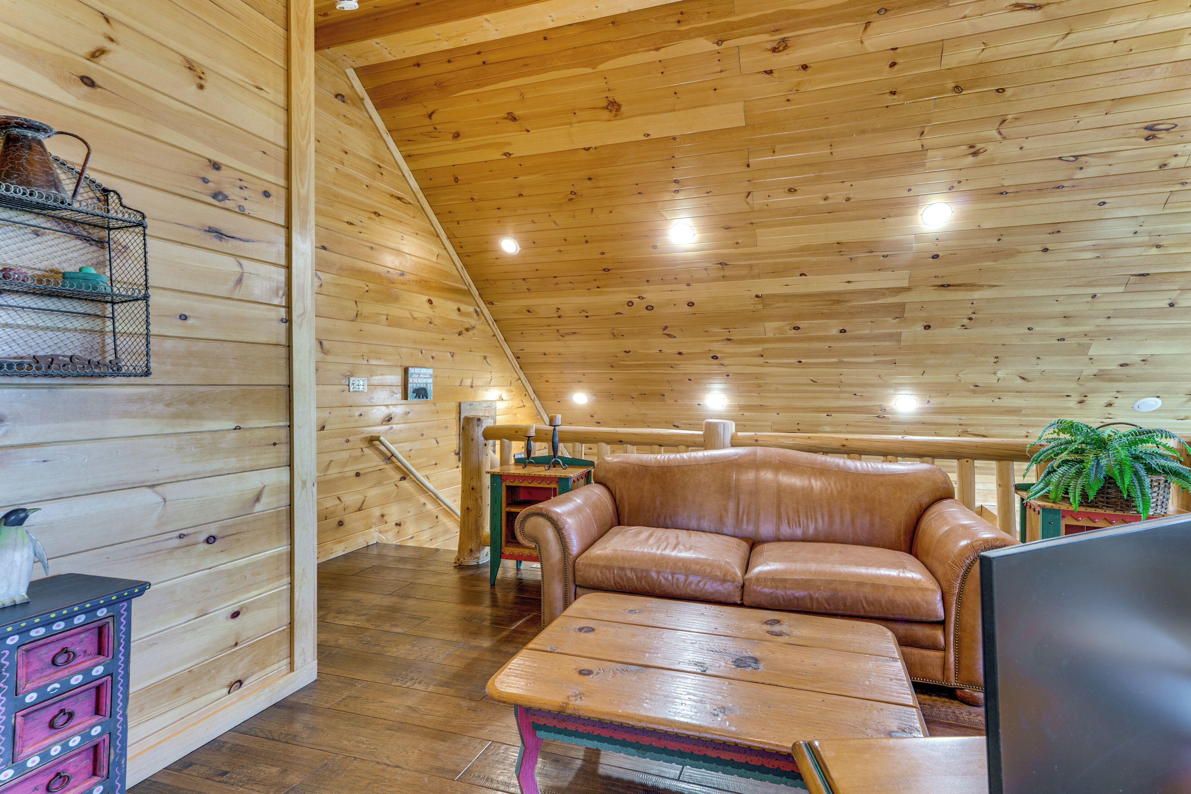 Interior de madera con un sofá de cuero, una mesa de madera y una estantería metálica con objetos.