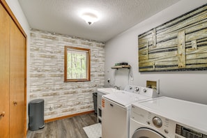 A laundry room with a washing machine, dryer, and a window with blinds. - 'the Blue Goose Chalet': Your Cozy Up North Escape (Gaylord)