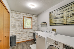 A laundry room with a washing machine, dryer, and a window with blinds.
