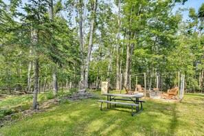 A picnic table in a forested area with a clear sky. - 'the Blue Goose Chalet': Your Cozy Up North Escape (Gaylord)