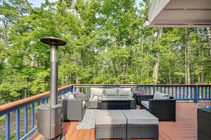 Une terrasse dotée de mobilier d’extérieur, d’un chauffage et offrant une vue sur une forêt.