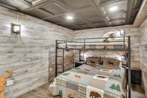 Ein Stockbett mit einem gemusterten Bettbezug, eine Wandleuchte und ein rustikales Holz-Kopfteil.