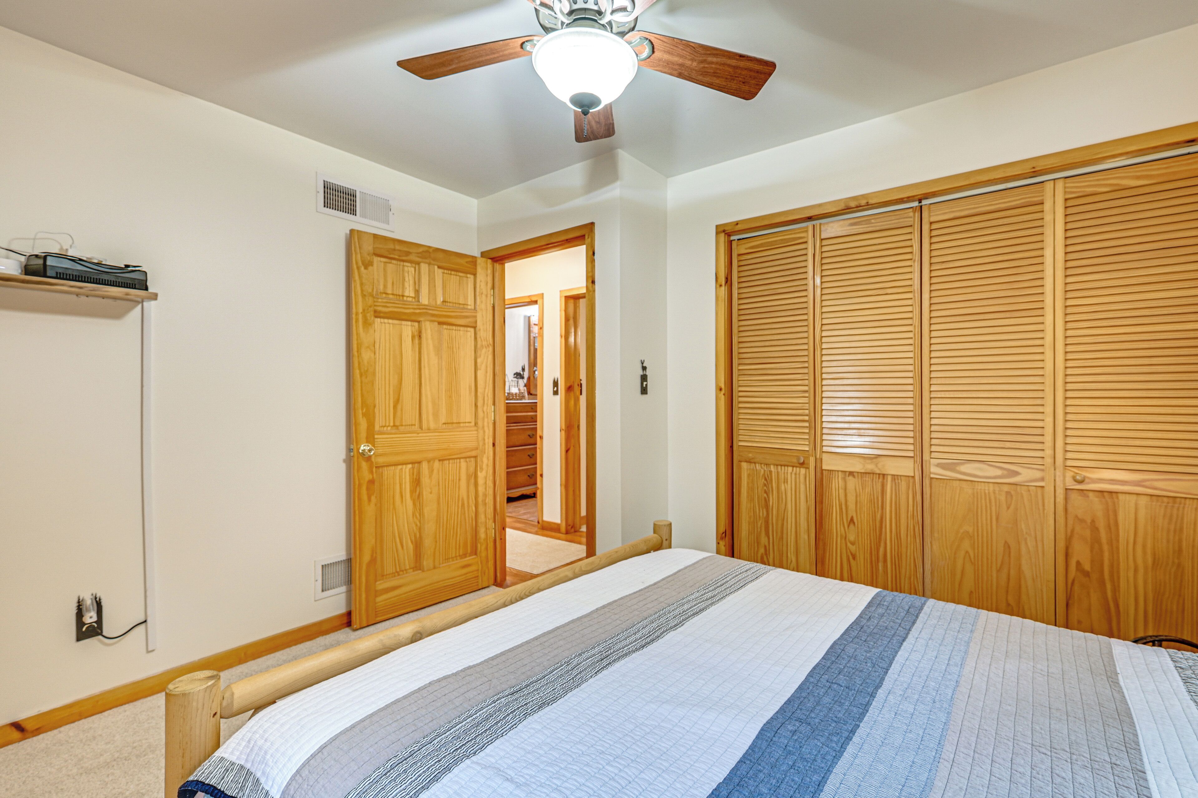 A bedroom with a bed, wooden wardrobe, and a ceiling fan.