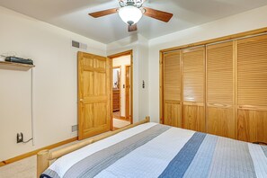 A bedroom with a bed, wooden wardrobe, and a ceiling fan. - River Access! Wooded Cabin in Great Cacapon (Great Cacapon)
