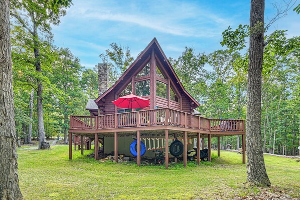 Une cabane en bois dotée d’un balcon, entourée d’arbres.