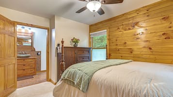 A bedroom with a wooden headboard, a bed with a striped bedspread, a nightstand, a dresser, and a ceiling fan.