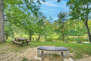 Ein Picknickplatz mit einer Bank und einem Tisch, umgeben von Bäumen und einem See.