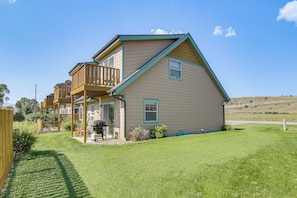 A two-story house with a balcony, a barbecue grill, and a well-maintained lawn. - Yellowstone Basecamp! Emigrant Home w/ Mtn Views (Emigrant)