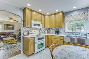 A kitchen with wooden cabinets, a microwave, an oven, and a stainless steel sink.