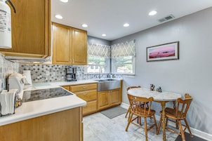 A kitchen with wooden cabinets, a built-in stove, a window with a view, and a dining table with chairs.