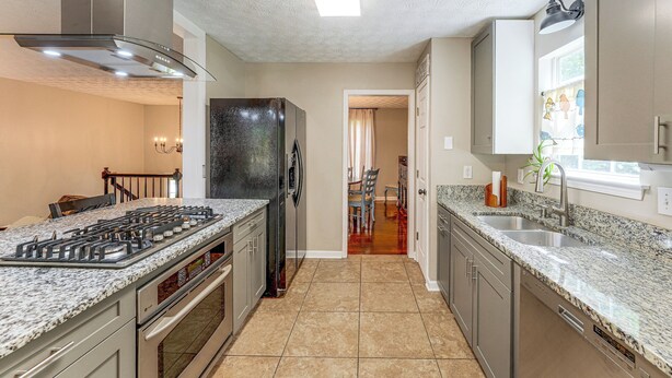 A modern kitchen with granite countertops, stainless steel appliances, and a tiled floor.