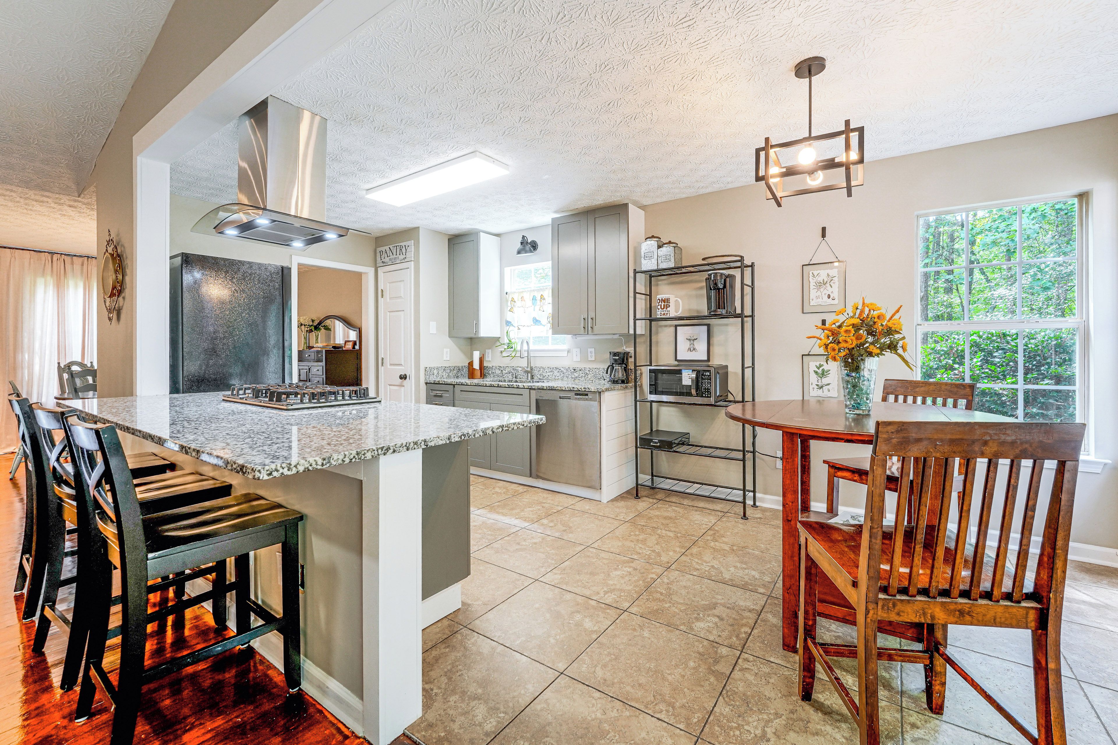 A modern kitchen with a central island, built-in appliances, and a dining area with a wooden table and chairs.