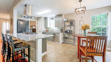 A modern kitchen with a central island, built-in appliances, and a dining area with a wooden table and chairs.