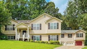 A two-story house with a front porch, a garage, and a well-maintained lawn.