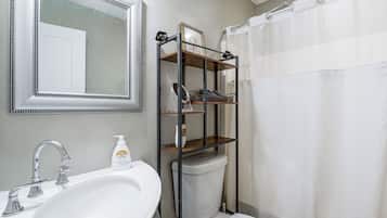 A bathroom with a white sink, a mirror, a toilet, and a shower curtain.