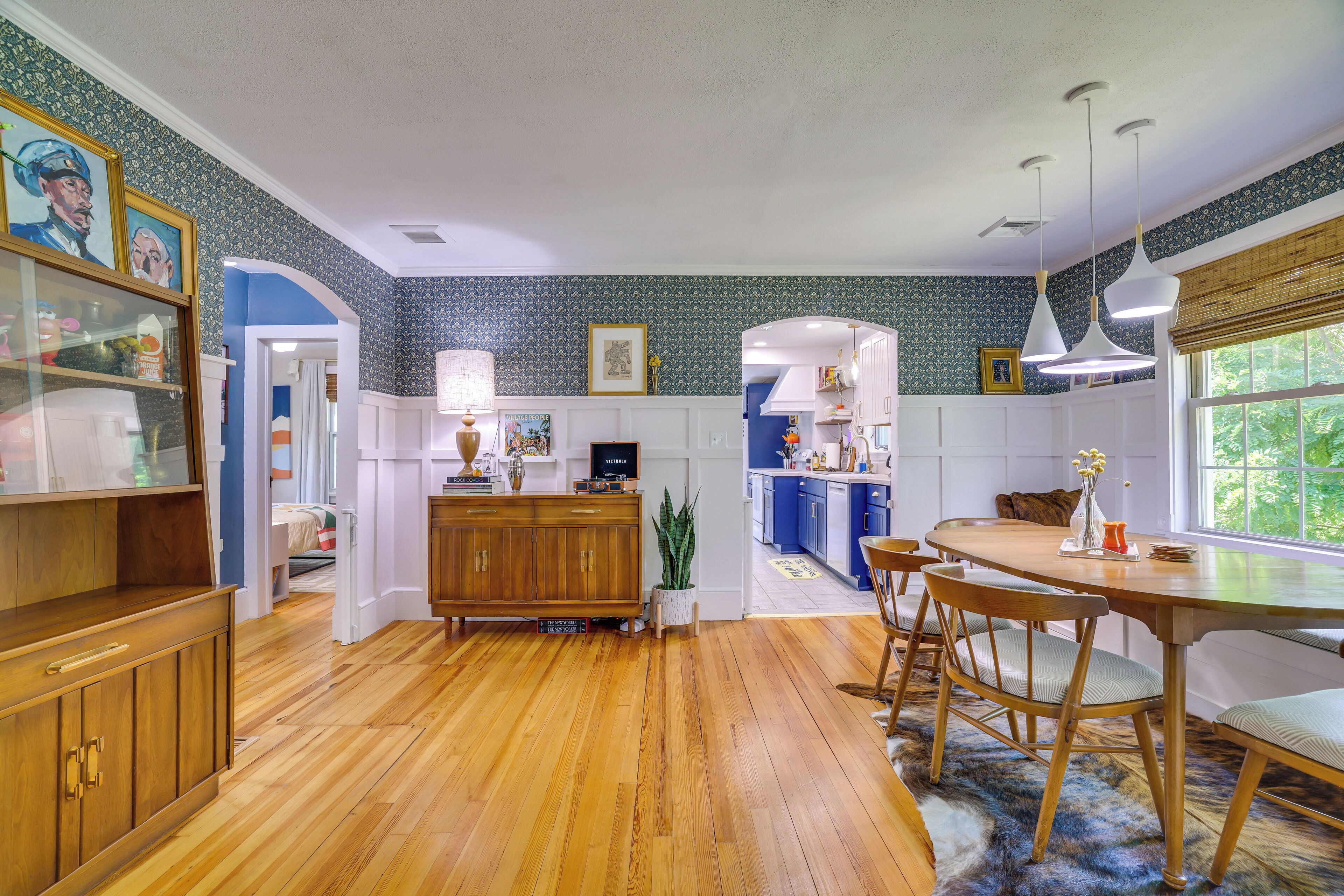 A spacious kitchen with wooden cabinets, a dining area with a round table, and a view of the garden through a window.