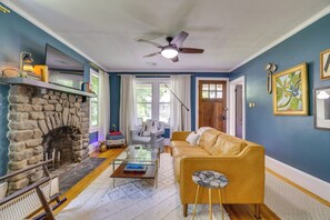 A living room with a stone fireplace, a sofa, a coffee table, and a ceiling fan. - Family-friendly Poconos Getaway 11 Mi to Kalahari! (Mountainhome)