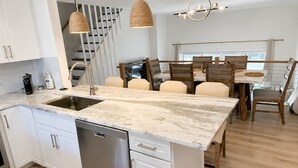 A modern kitchen with a central island, stainless steel appliances, and a dining area with wooden chairs. - Available 9/10 - 5/31/27 Coastal living, steps from the beach, 3-bedroom, (Sea Bright)