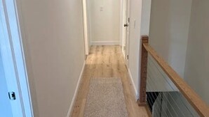 A narrow hallway with a wooden floor and a carpeted area. - Available 9/10 - 5/31/27 Coastal living, steps from the beach, 3-bedroom, (Sea Bright)