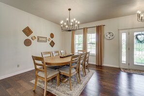 A dining room with a wooden table and chairs, a chandelier, and a clock on the wall. - 8-acre Family Reunion Retreat! 8 Mi to Bentonville (Pea Ridge)