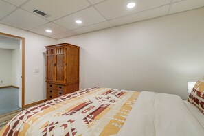 A bedroom with a bed, a wooden wardrobe, and a mirror on the wall. - 8-acre Family Reunion Retreat! 8 Mi to Bentonville (Pea Ridge)