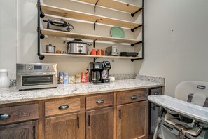 A kitchen with wooden cabinets, a built-in oven, a coffee maker, and a shelf with kitchenware. - 8-acre Family Reunion Retreat! 8 Mi to Bentonville (Pea Ridge)