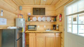 A compact kitchen with wooden cabinets, a stainless steel refrigerator, a microwave, a toaster, and a coffee maker.