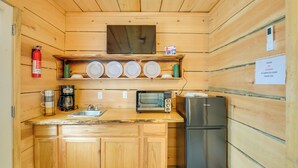 Una cocina compacta con armarios de madera, microondas, cafetera y refrigerador.
