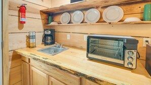 Una cocina compacta con horno tostador, cafetera y lavabo.