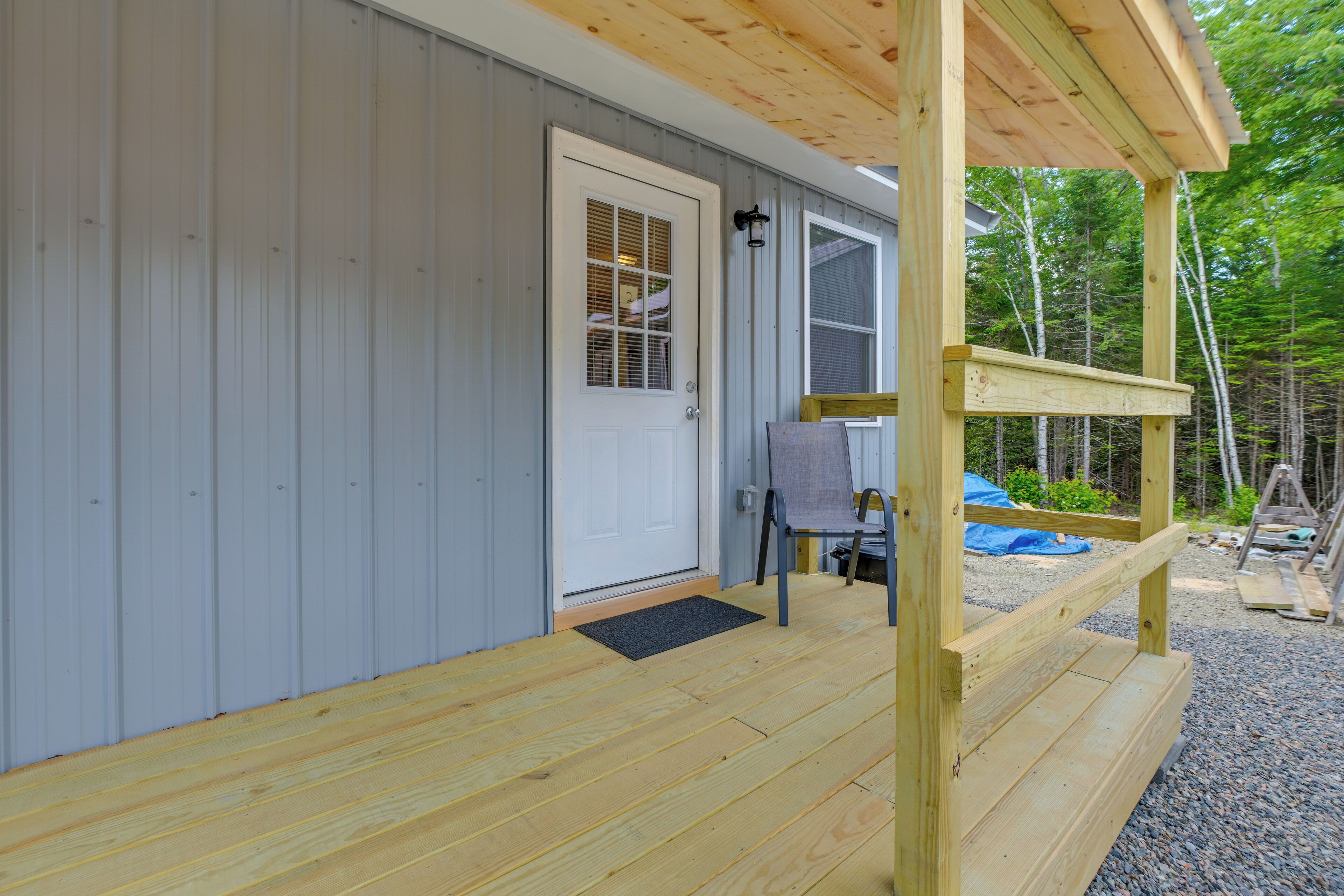 A wooden deck with a door and a bench, surrounded by a wooden fence.