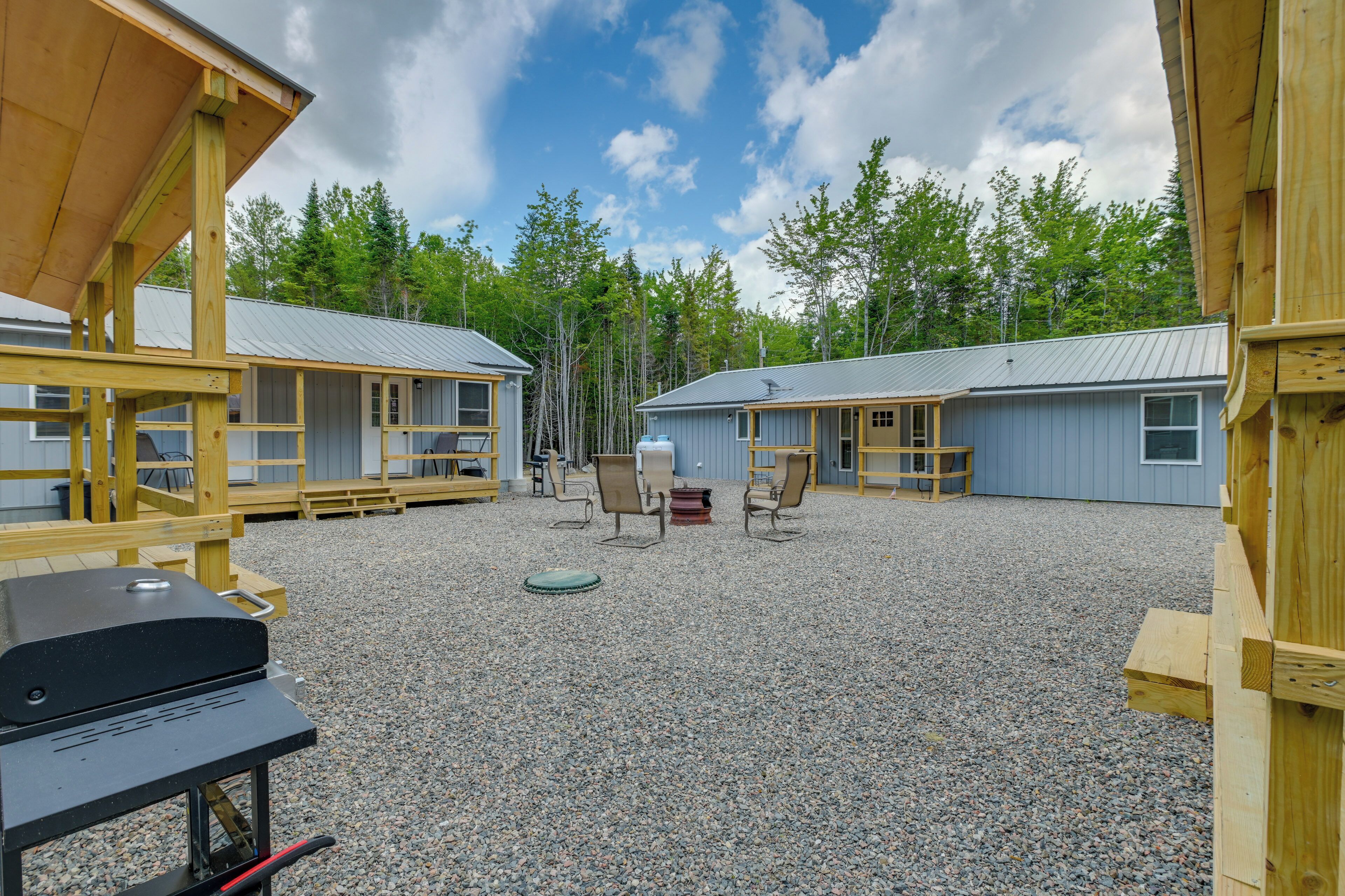 A campground with two cabins, outdoor seating, and a barbecue grill.