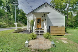 A small white building with a front porch, a wooden bench, and a stone pathway leading to the entrance. - Private Hot Tub & Yard! Modern Friendsville Escape (Friendsville)
