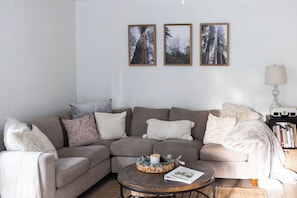 A living room with a sectional sofa, a coffee table, and three framed pictures on the wall. - Private Hot Tub & Yard! Modern Friendsville Escape (Friendsville)