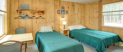 A wooden room with two beds, a table, and a chair.