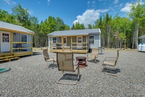 A cabin with a deck, outdoor seating, and a fire pit.