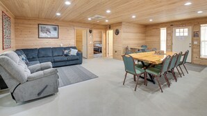 A cabin interior with a sofa, armchair, dining table, and chairs. - Maine Lodge Base Camp for Hiking, Riding & Fishing (Wesley)