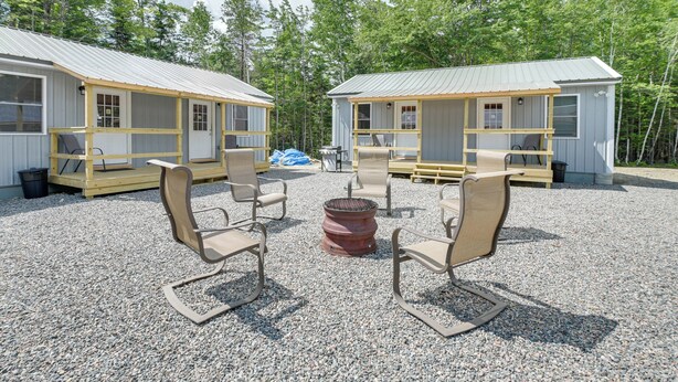 A campground with two cabins, outdoor seating, and a fire pit. - Maine Lodge Base Camp for Hiking, Riding & Fishing (Wesley)
