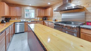 A kitchen with wooden cabinets, a stainless steel stove, and a dishwasher. - Maine Lodge Base Camp for Hiking, Riding & Fishing (Wesley)