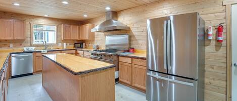 A modern kitchen with wooden paneling, stainless steel appliances, and a central island.