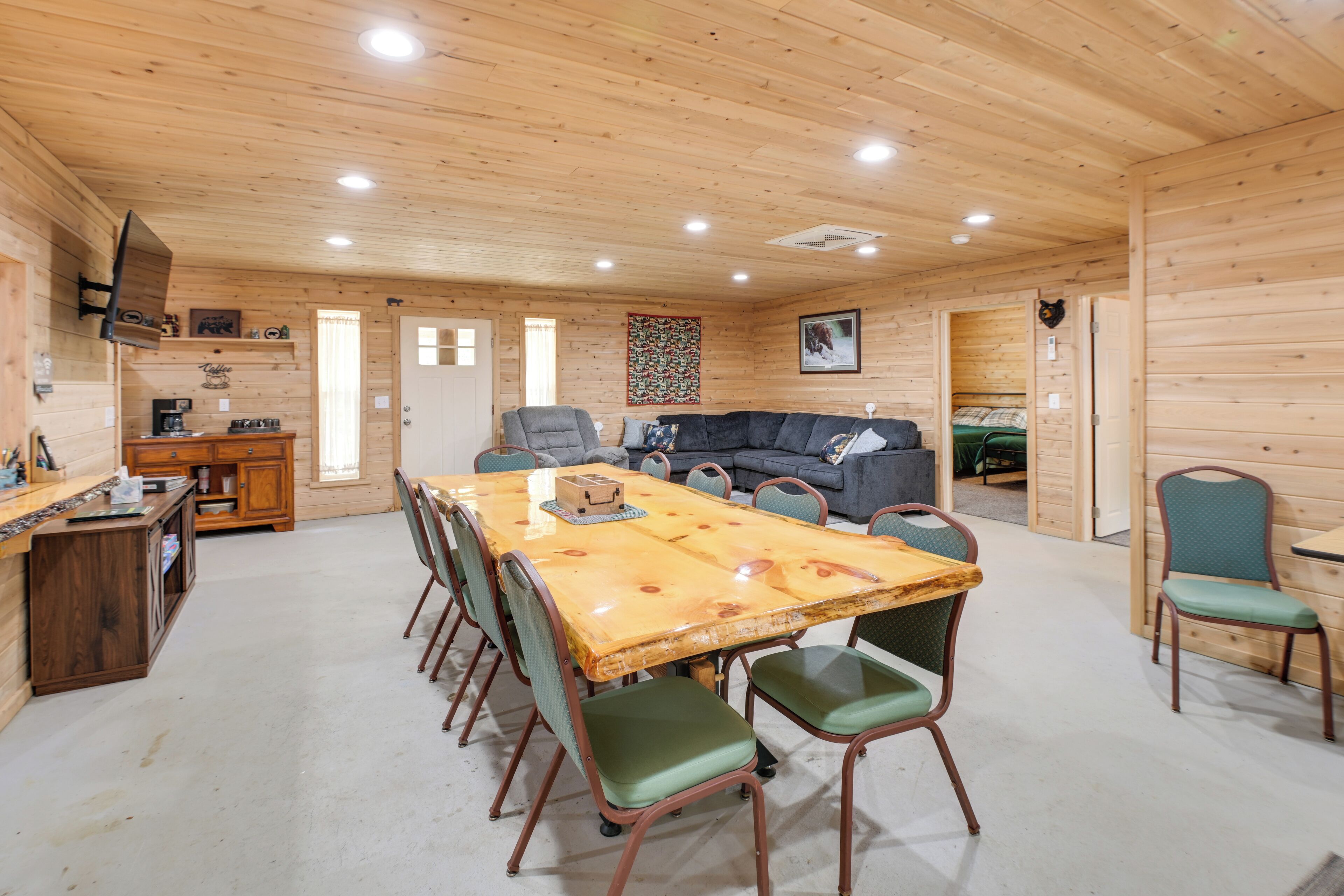 A wooden interior with a dining table, chairs, a sofa, and a kitchen area.