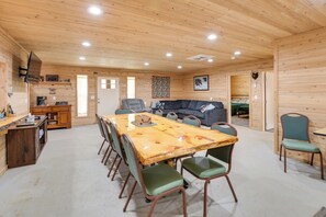 Un interior de madera con una mesa de comedor, sillas, un sofá y una zona de cocina.