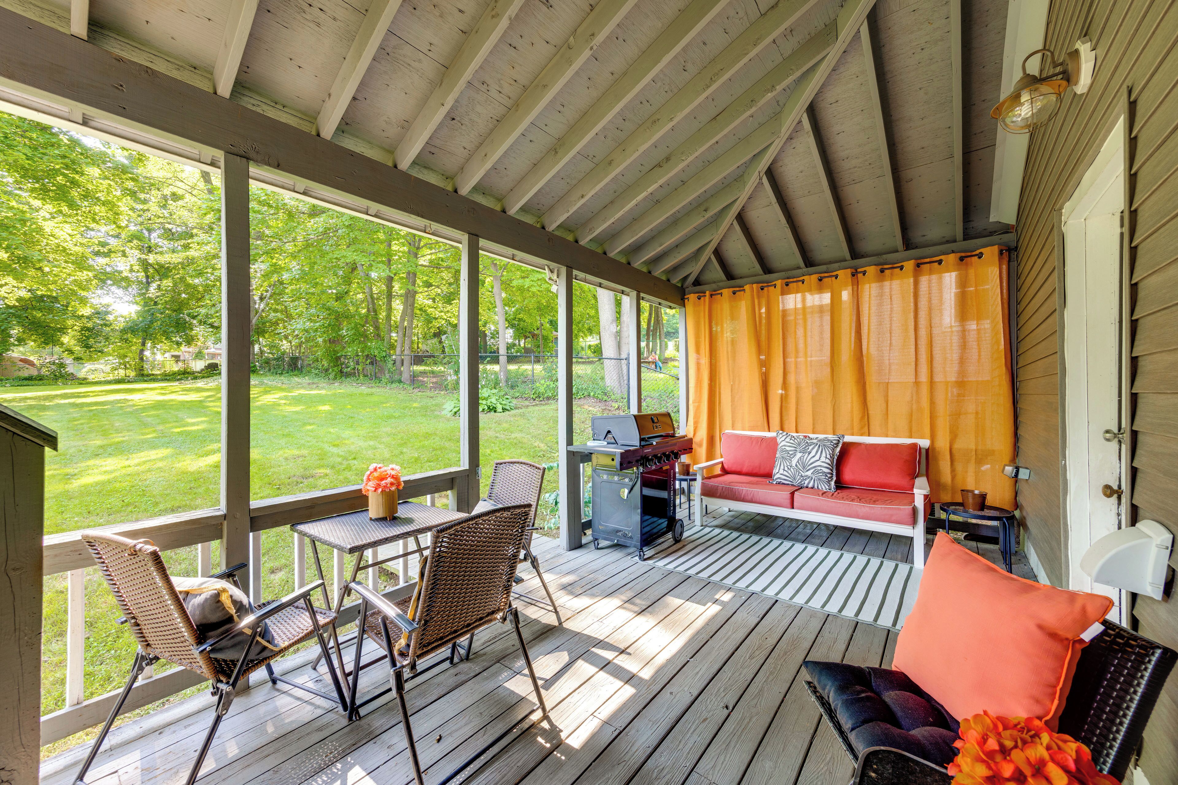 Een overdekt terras met een eettafel, stoelen en een bank.
